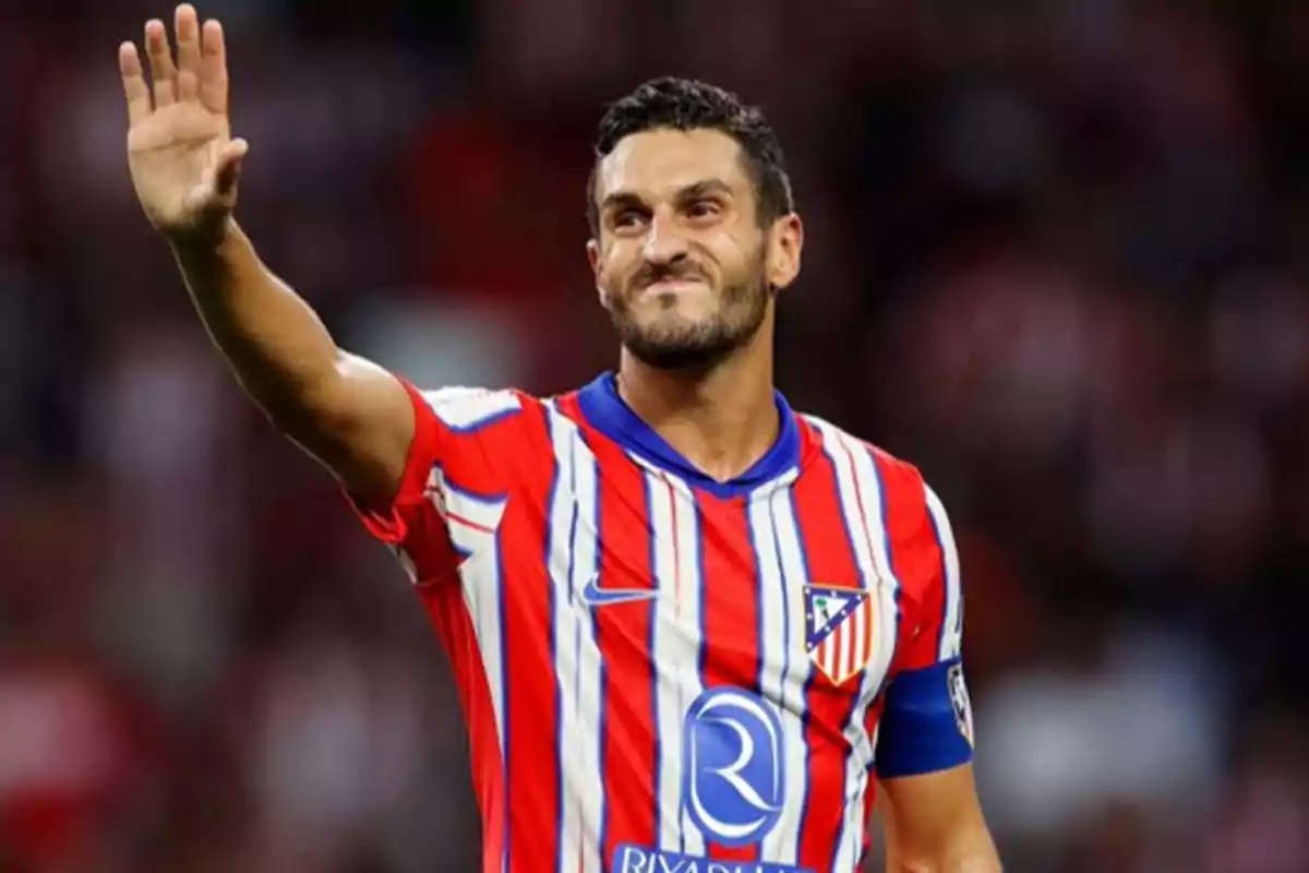 Soccer player in red and white uniform raising his hand in greeting