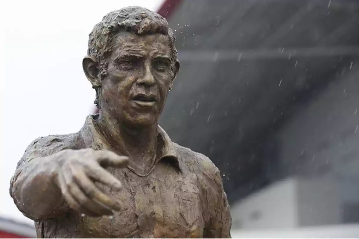 Statue of a man with his arm outstretched in the rain.