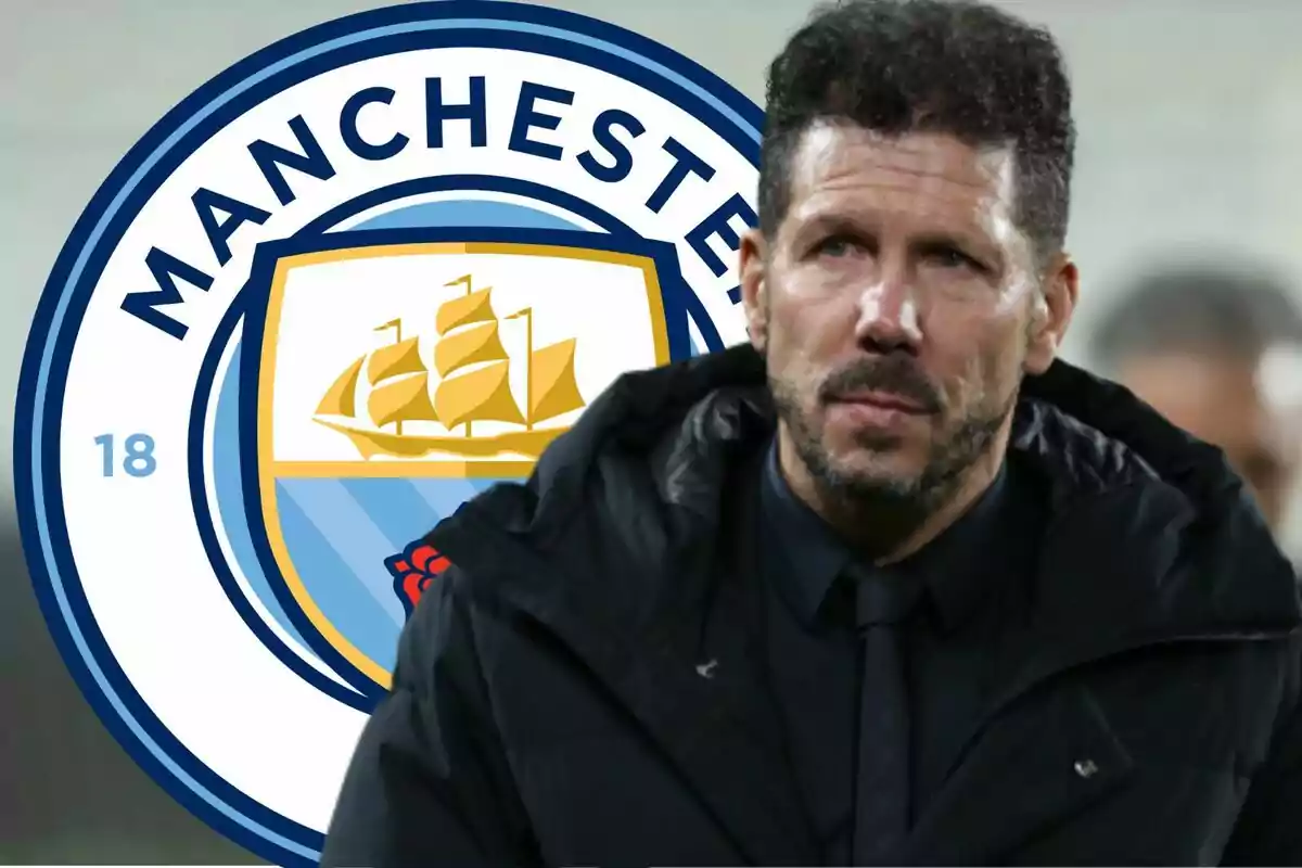 Man in black jacket in front of the Manchester City logo.