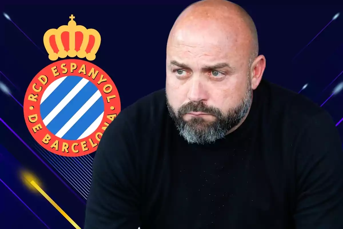 Man with a beard and a black t-shirt in front of the logo of the RCD Espanyol of Barcelona.