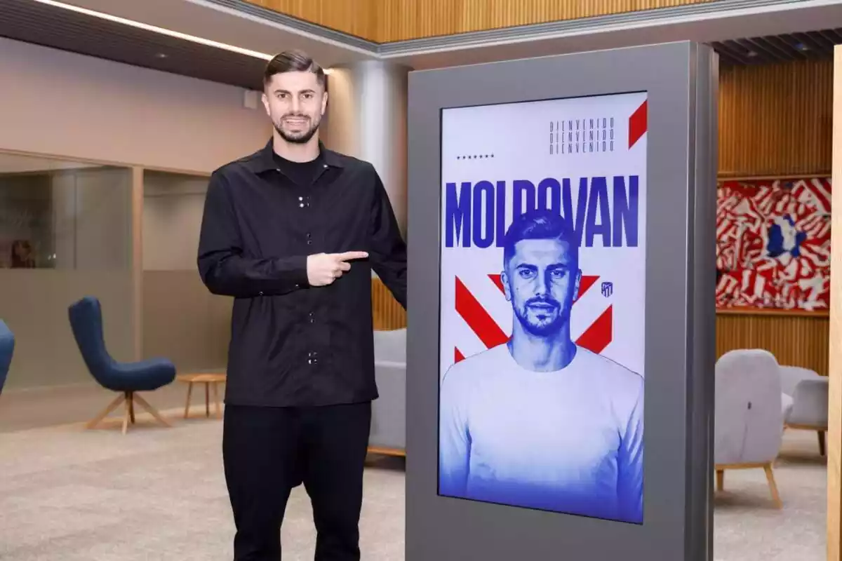 Moldovan posing next to an image of his signing for Atlético de Madrid