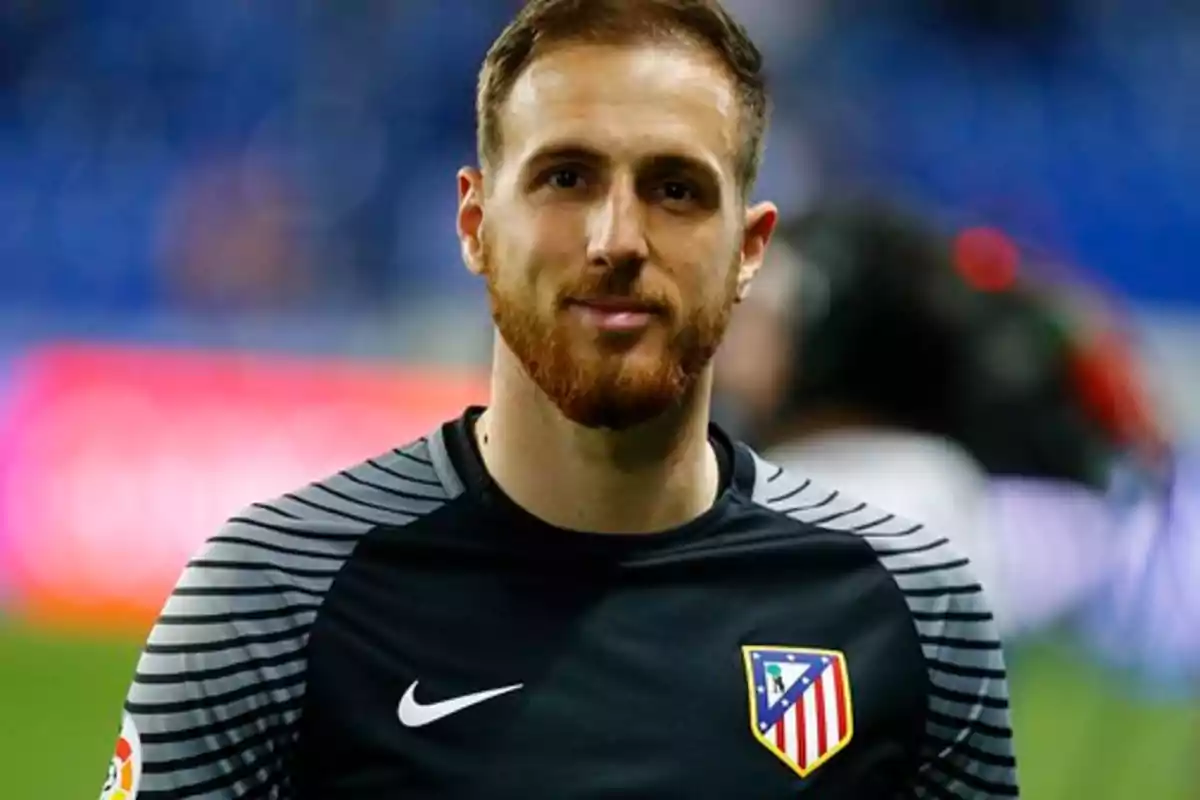 A bearded football player wearing an Atlético de Madrid shirt.