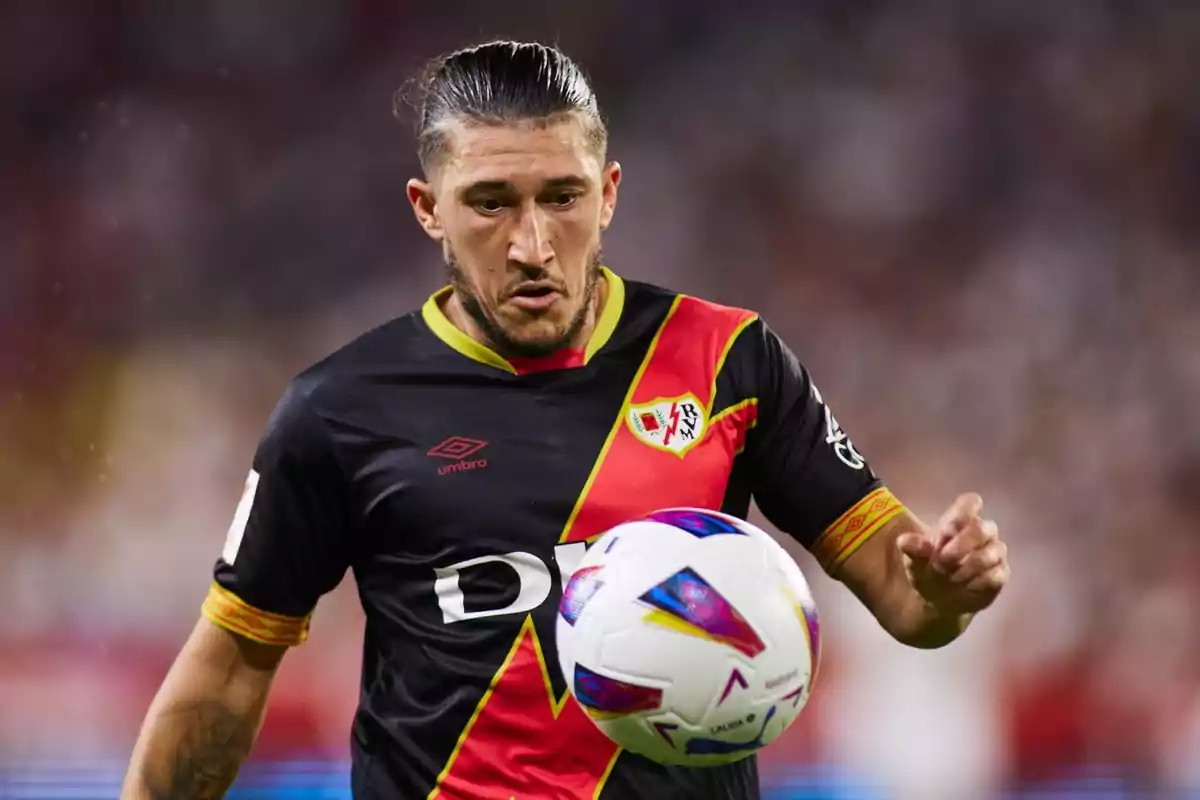 Soccer player in black and red uniform controlling a ball in a match.