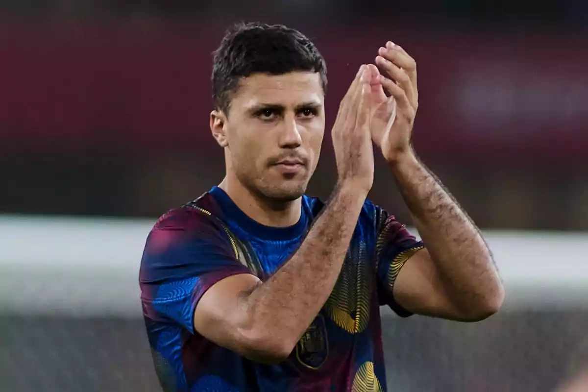 Football player applauding on the field wearing a colorful jersey.