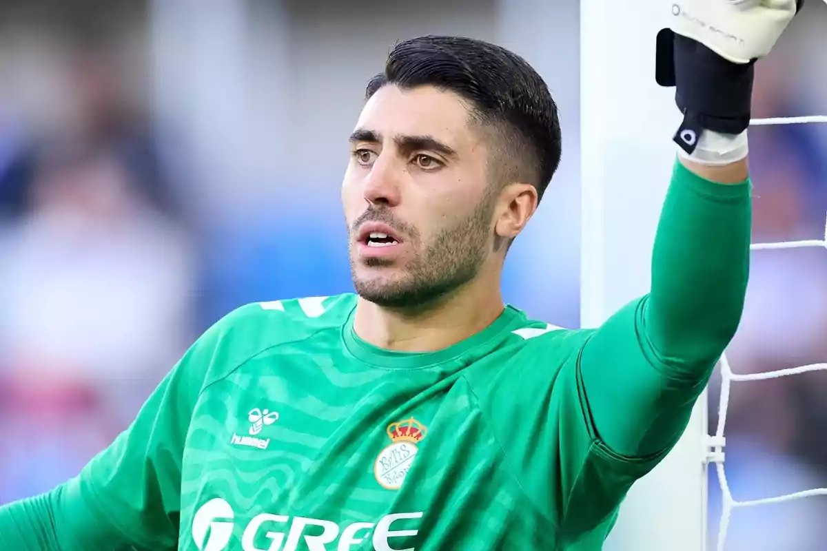 Soccer goalkeeper in green uniform leaning on the goal post.