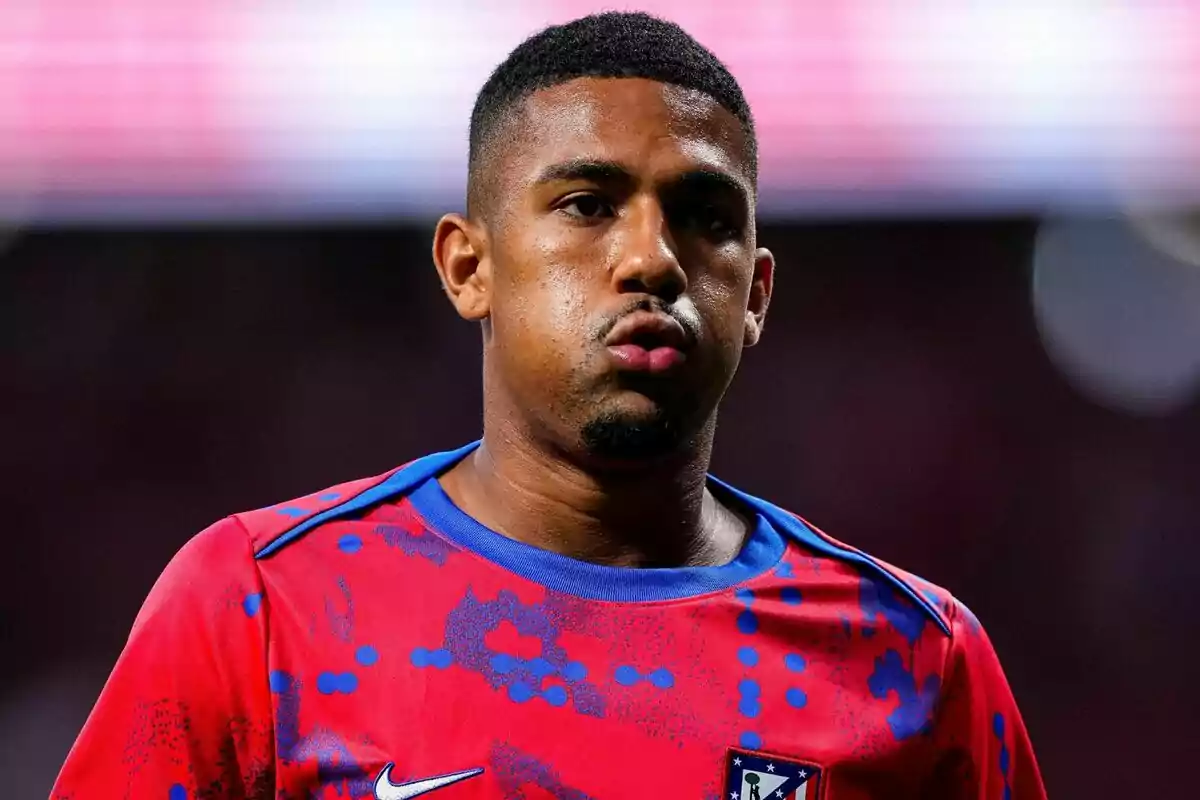 Football player in red and blue Atlético de Madrid shirt on the field.