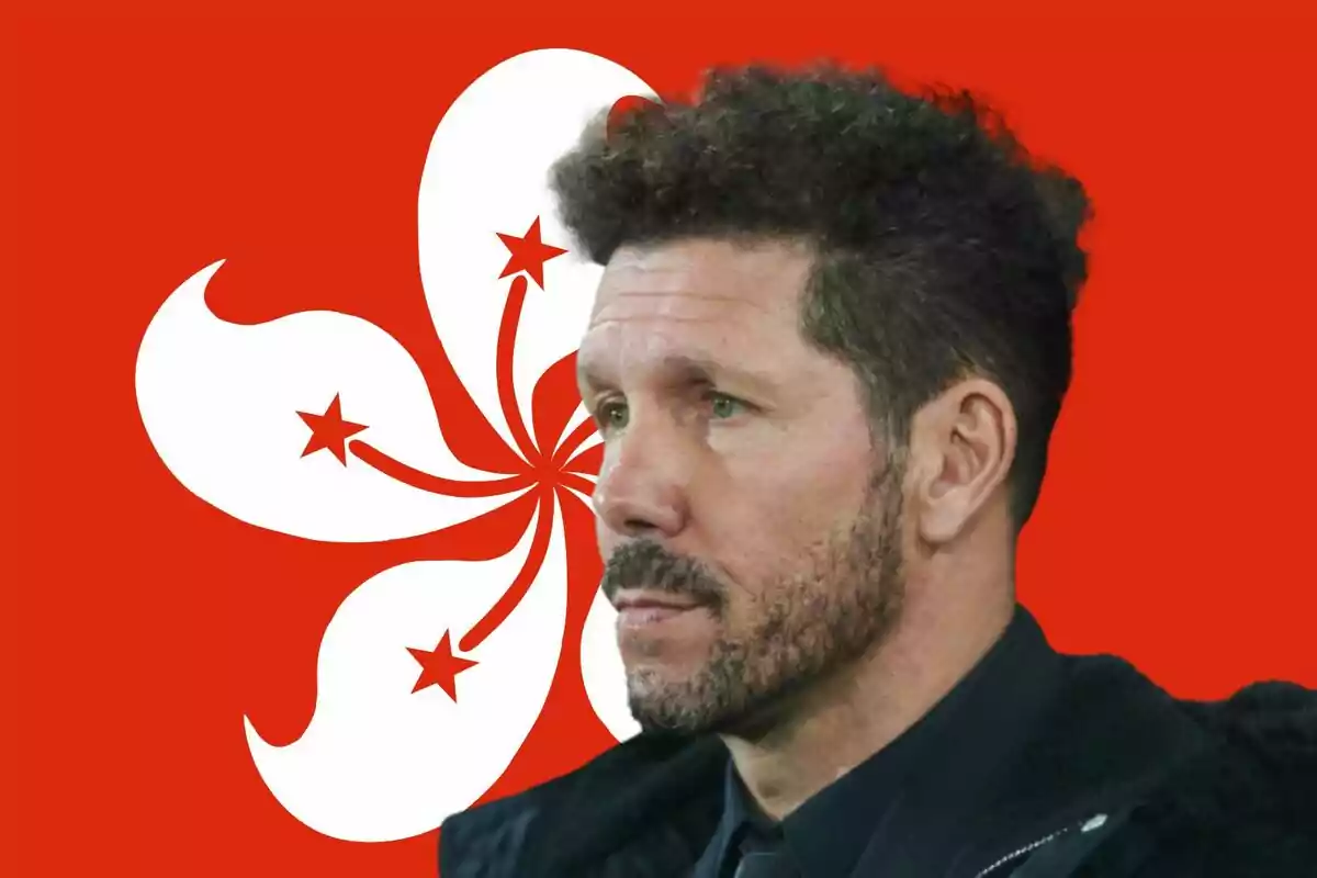 Man with a beard and curly hair in front of a red flag with a stylized white flower.