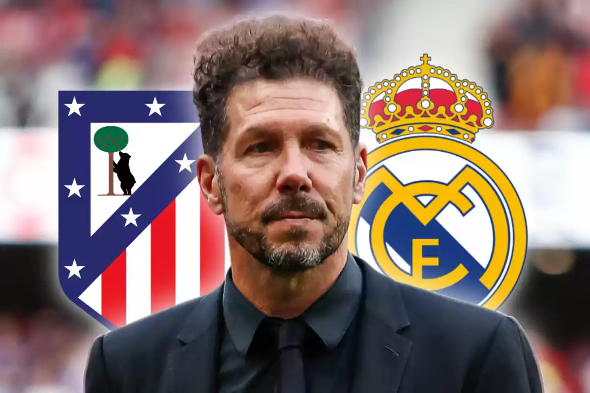 A man in a black suit stands in front of the Atlético de Madrid and Real Madrid crests.