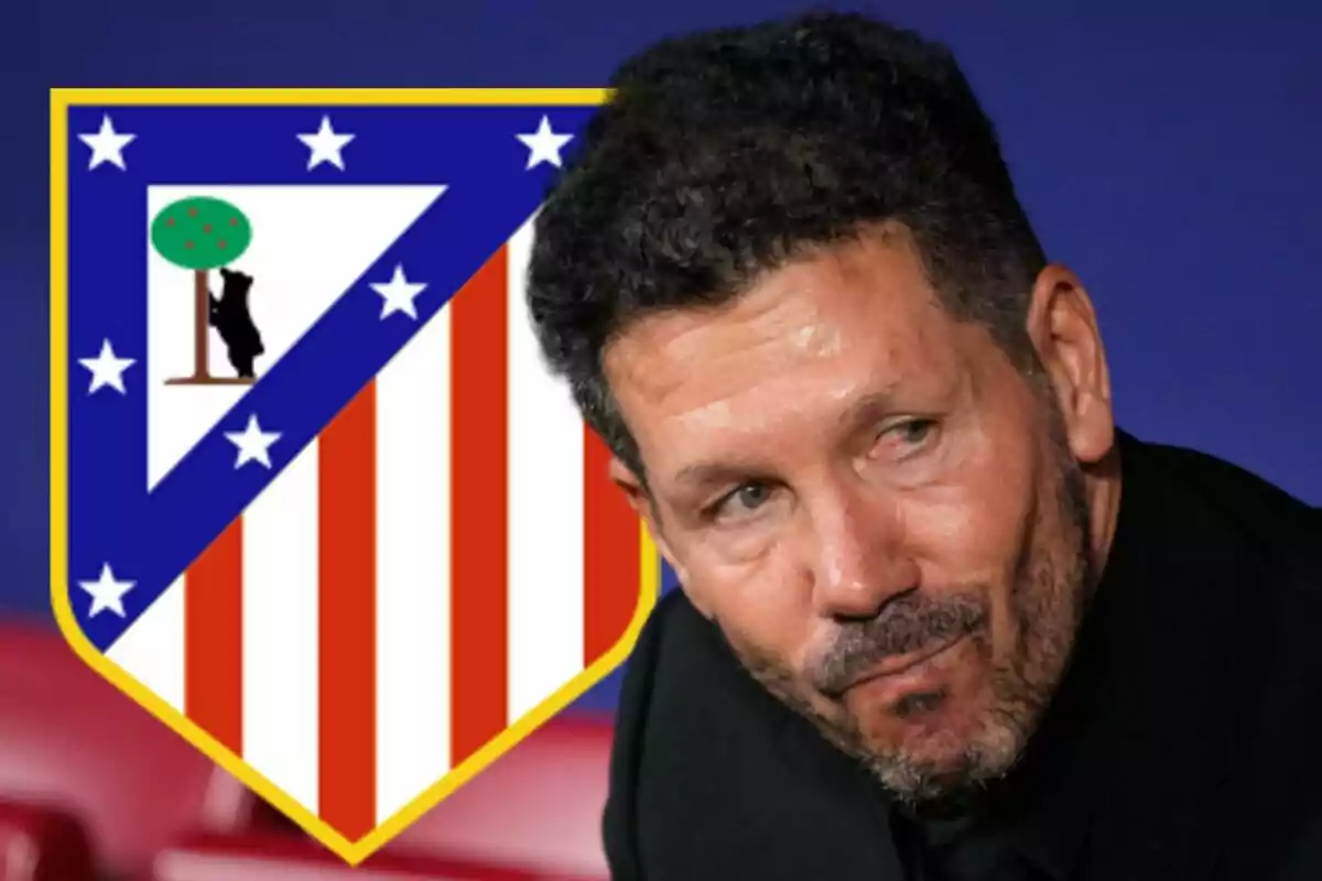 A man with a beard and dark hair, dressed in black, stands in front of the Atlético de Madrid crest.