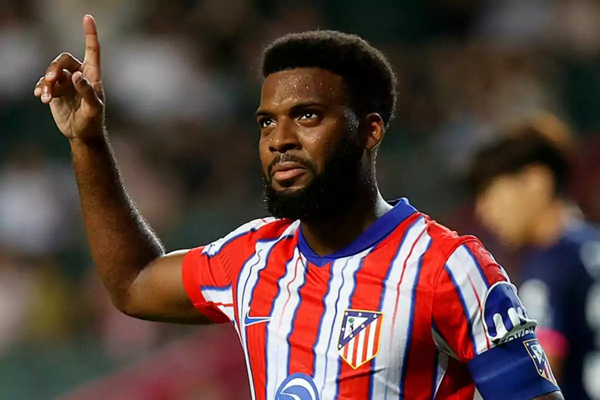 Football player in Atlético de Madrid uniform raising a finger.