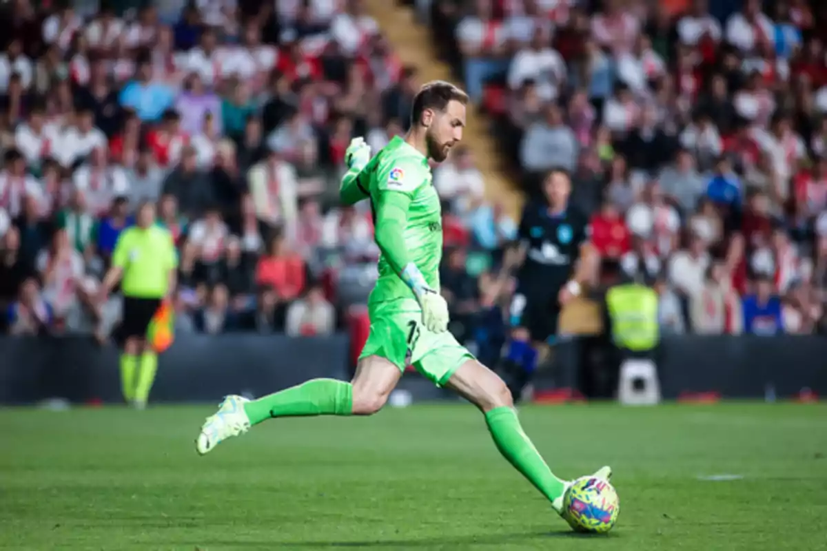 A soccer goalkeeper dressed in green kicks the ball in a stadium full of spectators.